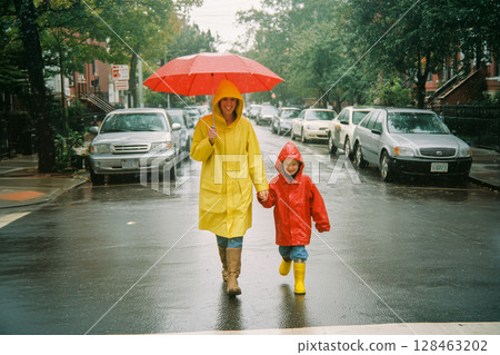 A woman and a child are walking down a street in the rain, holding hands A woman and a child are walking down a street in the rain, holding hands 128463202