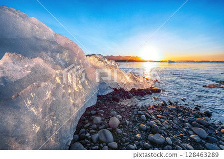 Impressive pieces of the iceberg sparkle on famous Diamond Beach at  Jokulsarlon lagoon during sunset. 128463289