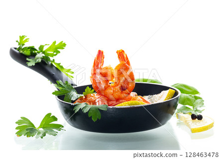 Appetizing seafood in a frying pan with lemon and herbs isolated on white Appetizing seafood in a frying pan with lemon and herbs isolated on white 128463478