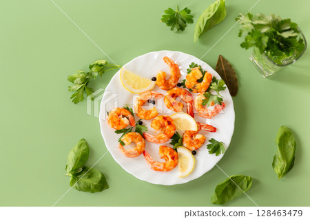 Delicious sea shrimps with lemon in a plate isolated on green 128463479