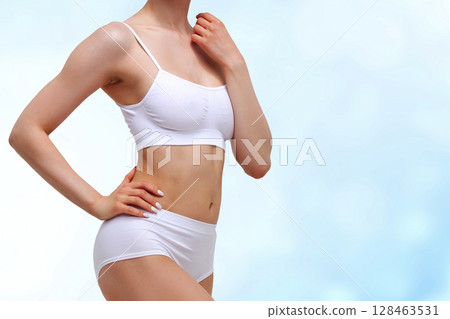Beautiful slim woman in white lingerie against an abstract blue background 128463531