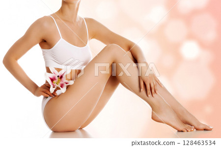 Beautiful female body with big lily flower against an abstract background with circles and copyspace 128463534