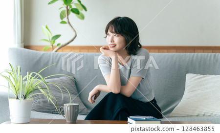 Smiling woman sitting on sofa in living room Smiling woman sitting on sofa in living room 128463855
