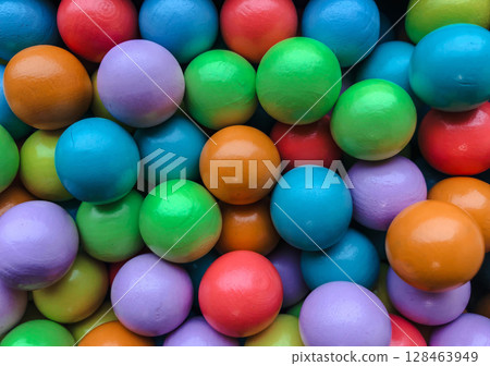 A vibrant and colorful overhead shot of numerous wooden or painted balls, tightly packed together, creating a lively full-frame texture. A vibrant and colorful overhead shot of numerous wooden or painted balls, tightly packed together, creating a lively full-frame texture. 128463949