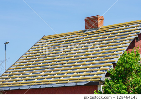 Red House Roof in Progress with Wooden Battens and Underlayment on a Bright Spring Day 128464145