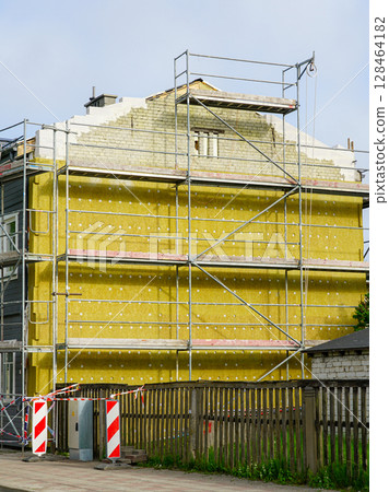 Scaffolding and Thermal Insulation Panels on Residential Building Exterior Wall Under Renovation 128464182