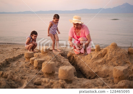 Family bonds strengthen while building sandcastles at sunset Family bonds strengthen while building sandcastles at sunset 128465095