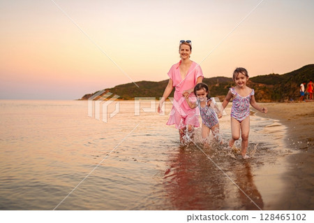 Family plays and laughs together during sunset at the beach 128465102