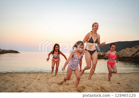 Family plays joyfully on the beach during a beautiful sunset 128465120