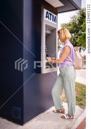 European traveler withdraws cash at an ATM in Greece 128465122