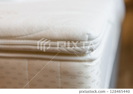 The close-up captures the edge of a mattress with a visible zipper, highlighting the soft fabric and detailed stitching in a cozy and well-lit environment The close-up captures the edge of a mattress with a visible zipper, highlighting the soft fabric and detailed stitching in a cozy and well-lit environment 128465440