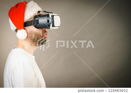 Man in virtual reality goggles and santa hat 128465652