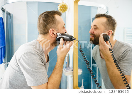 Man shaving trimming his beard 128465655