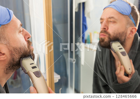 Man shaving trimming his beard Man shaving trimming his beard 128465666