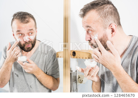 Man applying moisturizer cream in bathroom Man applying moisturizer cream in bathroom 128465670