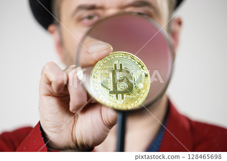 Man looking at bitcoin through magnifying glass Man looking at bitcoin through magnifying glass 128465698