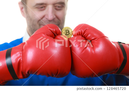 Man in boxing gloves holding bitcoin Man in boxing gloves holding bitcoin 128465720
