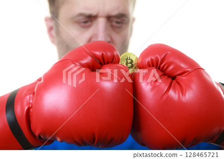 Man in boxing gloves holding bitcoin Man in boxing gloves holding bitcoin 128465721