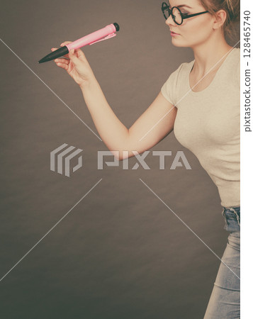 Woman holding big oversized pencil thinking about something Woman holding big oversized pencil thinking about something 128465740