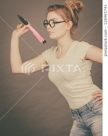 Woman holding big oversized pencil thinking about something Woman holding big oversized pencil thinking about something 128465741