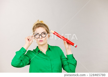 Woman confused thinking, big pencil in hand Woman confused thinking, big pencil in hand 128465780
