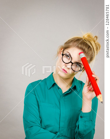 Woman confused thinking, big pencil in hand 128465781