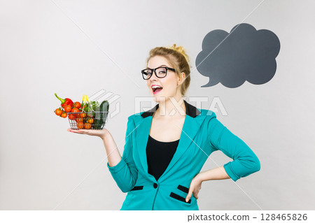Woman holds shopping cart with vegetables, copy space 128465826