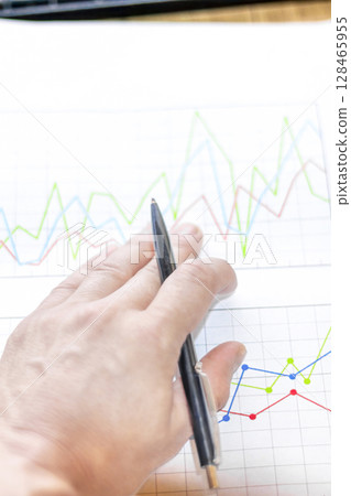 Businessman analyzes market printed on paper to improve business, business concept and strategy, blurry photo Businessman analyzes market printed on paper to improve business, business concept and strategy, blurry photo 128465955