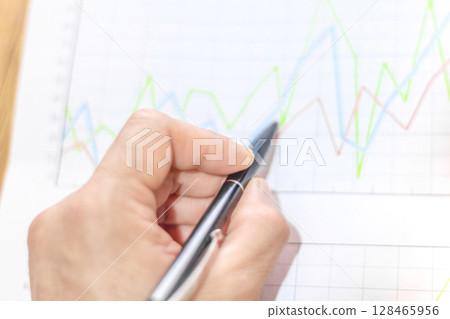 Businessman analyzes market printed on paper to improve business, business concept and strategy, blurry photo Businessman analyzes market printed on paper to improve business, business concept and strategy, blurry photo 128465956