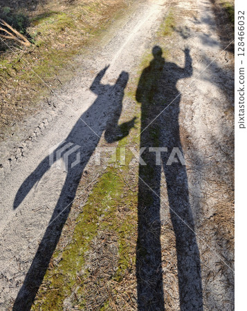 Long shadows of father and son on forest path in the evening at sunset 128466032