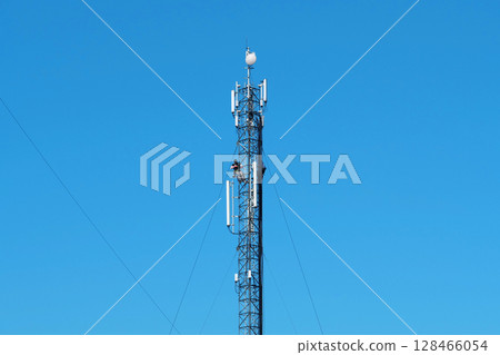 Two workers repair cell tower. High-altitude work. Laying new cables Two workers repair cell tower. High-altitude work. Laying new cables 128466054