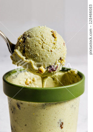 ice cream flavored with pistachios in a plastic cup on a white background 128466083