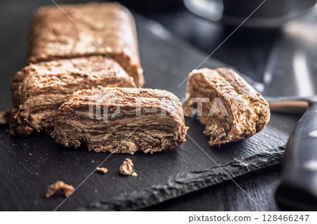 Halva with cocoa. Sweet oriental dessert on black table. 128466247