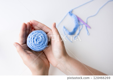 Woman holding blue yarn ball with crochet hooks on white background 128466269