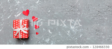 Valentine day composition: red gift box with bow and heart. Christmas present. View from above. Space for text. Holday greeting card 128466330