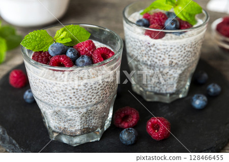 Healthy breakfast or morning with chia seeds vanilla pudding raspberry and blueberry berries on table background, vegetarian food, diet and health concept. Chia pudding with raspberry and blueberry Healthy breakfast or morning with chia seeds vanilla pudding raspberry and blueberry berries on table background, vegetarian food, diet and health concept. Chia pudding with raspberry and blueberry 128466455