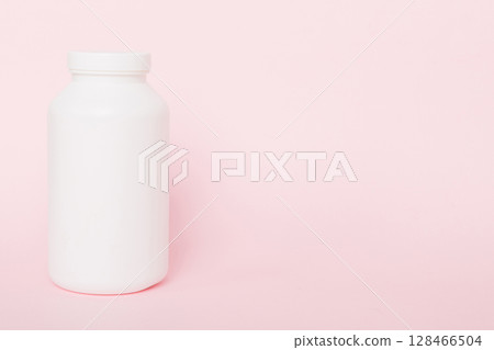 supplement pills with medicine bottle health care and medical top view. Vitamin tablets. Top view mockup bottle for pills and vitamins with green leaves, natural organic bio supplement, copy space 128466504