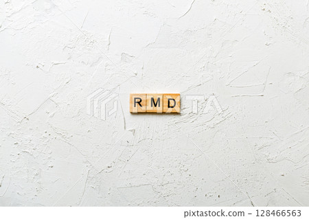RMD word written on wood block. Required Minimum Distributions text on table, concept 128466563