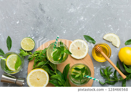 Caipirinha, Mojito cocktail, vodka or soda drink with lime, mint and straw on table background. Refreshing beverage with mint and lime in glass top view flat lay Caipirinha, Mojito cocktail, vodka or soda drink with lime, mint and straw on table background. Refreshing beverage with mint and lime in glass top view flat lay 128466568