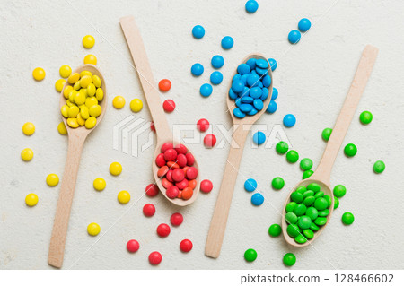 delicious colorful sweet candies on spoon on colored background . Confectionery decor top view with copy space 128466602