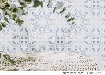 Empty white wicker podium for presentation or advertising. Round product display opposite tile wall with eucalyptus leaves and shadows. Concept of scene stage for natural products or promotion sale 128466776