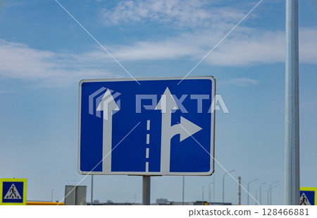 Traffic sign displays arrows showing the option to continue straight or turn right at an intersection in sunny weather Traffic sign displays arrows showing the option to continue straight or turn right at an intersection in sunny weather 128466881