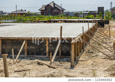 Workers are setting up a concrete foundation for a residential project in a growing suburban neighborhood under clear skies Workers are setting up a concrete foundation for a residential project in a growing suburban neighborhood under clear skies 128466902
