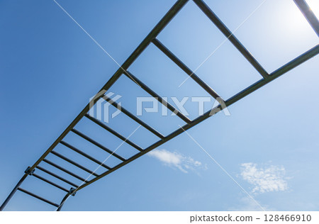 Brightly illuminated horizontal gym bars stretch across the sky, emphasizing fitness and an active lifestyle in a vibrant atmosphere 128466910