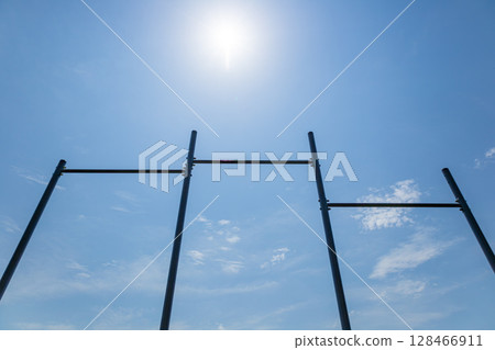 Parallel horizontal bars stand tall against a blue sky, perfect for various workout routines and promoting an active lifestyle outdoors 128466911
