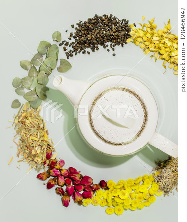 Organic herbal tea. Concept of healing herbal tea, healthy drink and home herbal apothecary. Dry wild growing flowers and herbs with teapot on blue background. Flat lay, vertical format Organic herbal tea. Concept of healing herbal tea, healthy drink and home herbal apothecary. Dry wild growing flowers and herbs with teapot on blue background. Flat lay, vertical format 128466942