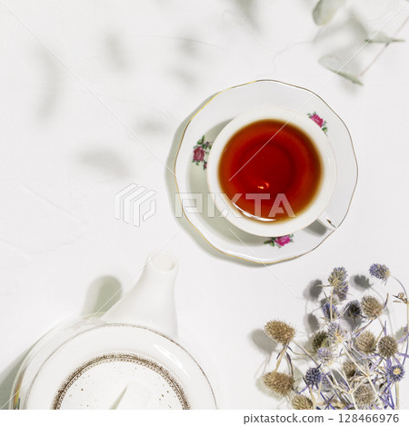 Tea time. Healing natural herbal tea with wild plants and flowers. Sustainable morning composition with cup of tea, teapot and dry flowers on white background. Flat lay 128466976