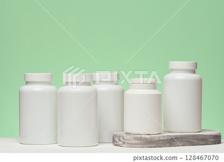 Several white plastic jars with pills on a green background. Items related to medicine and health care 128467070