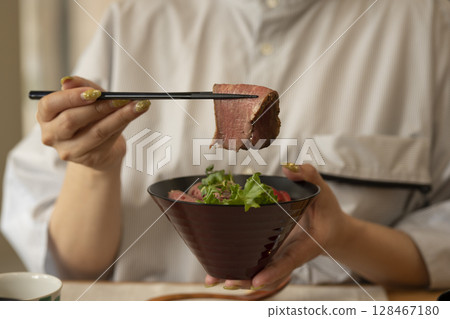 Woman eating roast beef bowl 128467180