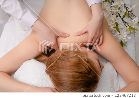 Woman receiving massage in serene studio environment for relaxation 128467218